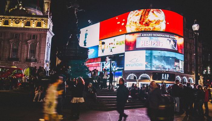 Crowd of people under digital billboards